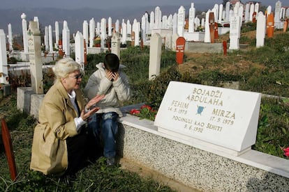 Muhammed Bojadzi y su madre Halida Bojadzi, rezan en un cementerio musulman ante las tumbas de sus dos hijas fallecidas por el bombardeo de su casa por parte del ejército serbio en 1992, en la ciudad de Sarajevo,