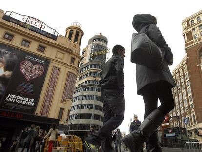 Personas pasan por delante del Palacio de la Prensa (derecha), en la plaza de Callao.