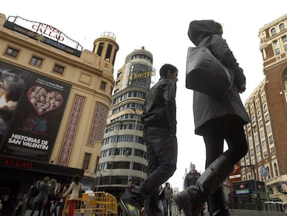 Personas pasan por delante del Palacio de la Prensa (derecha), en la plaza de Callao.