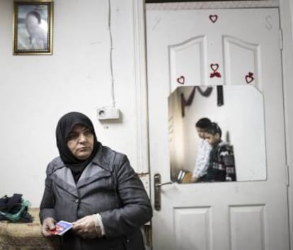 Nahla, en su casa con sus dos hijos pequeños. El retrato en la pared es de su difunto marido.
