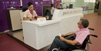 Un viajero de Renfe con movilidad reducida es atendido por una operaria de Atendo.