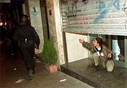 Una manifestante a la puerta de un local con el cierre casi bajado grita a unos policías.