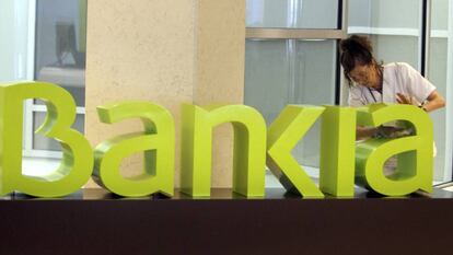 Una trabajadora limpia el logo de Bankia.