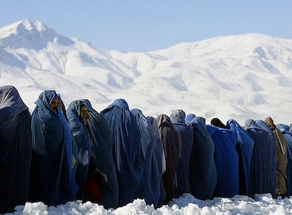 Viudas afganas cubiertas con el <i>burka</i> se alinean para conseguir raciones de comida ante un centro de distribución de una organización internacional en Kabul.