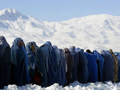Viudas afganas cubiertas con el <i>burka</i> se alinean para conseguir raciones de comida ante un centro de distribución de una organización internacional en Kabul.