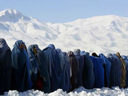 Viudas afganas cubiertas con el <i>burka</i> se alinean para conseguir raciones de comida ante un centro de distribución de una organización internacional en Kabul.