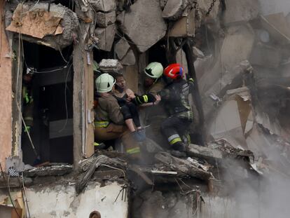 Los trabajadores de emergencia rescatan a una mujer de entre los restos del edificio residencial destruido por un misil ruso en Dnipró, este domingo.