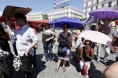 Turistas se protegen del calor en la Puerta del Sol de Madrid.