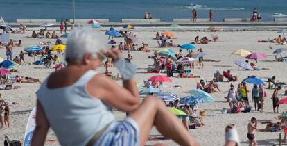 Una persona sentada frente a la playa en A Mariña (Lugo/Galicia).