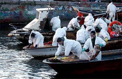 Los voluntarios limpian las barcas en Cangas (Pontevedra).