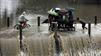 Un grupo de filipinos, montados en un carro improvisado, cruza una presa desbordante durante una lluvia torrencial en la ciudad de Las Pinas, al sur de Manila, (Filipinas).