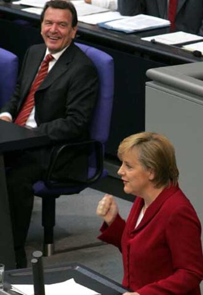 Schröder escucha a Merkel durante su intervención en el Parlamento.
