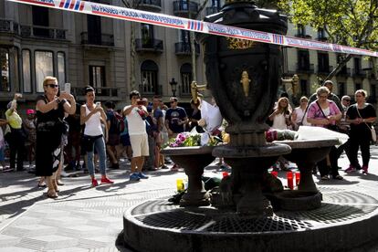 Varias personas fotografían la fuente de Canaletas, en las Ramblas de Barcelona, en la que se han depositado velas y flores después del atentado ocurrido ayer por la tarde en un atropello masivo en el que una furgoneta arrolló a los peatones que paseaban por la zona y que hasta el momento, se ha saldado con 13 personas muertas y más de 50 heridas.