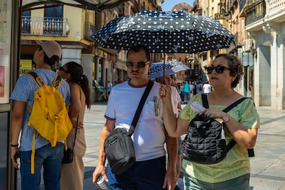 Unos turistas se protegen del calor con una sombrilla este domingo en Toledo, donde se ha activado el aviso naranja por altas temperaturas. 
