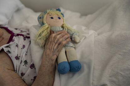 26 de abril de 2020. Una anciana sostiene una muñeca en la habitación de la residencia en la que permanece confinada a causa de la pandemia en Badalona, Barcelona