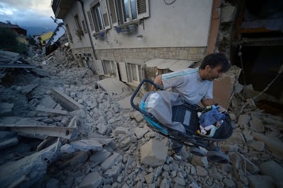 Um homem leva um carrinho de bebê pelos escombros, após o terremoto de Amatrice.