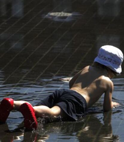 Un niño se refresca del calor en Madrid Río.