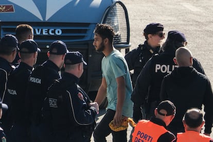 Un migrante camina junto a agentes de la policía italiana, este miércoles  tras desembarcar en el puerto de Shengjin.