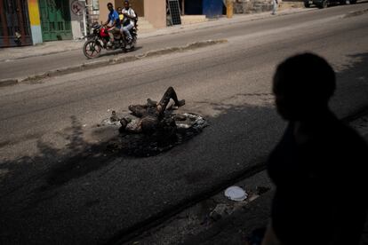 La gente pasa junto al cuerpo de un hombre que fue asesinado e incendiado en el área de Delmas, en Puerto Príncipe (Haití), el 5 de junio. 