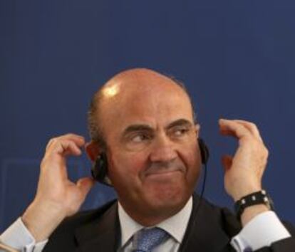 Spanish Economy Minister Luis de Guindos adjusts his headphones during a joint news conference with German Finance Minister Wolfgang Schaeuble in Loja, near Granada, April 29, 2013. Spain and Germany have agreed to launch a joint government-sponsored financing programme for small- and medium-size companies, their economy and finance ministers said on Monday. REUTERS/Pepe Marin (SPAIN - Tags: BUSINESS POLITICS) SPAIN-GERMANY/