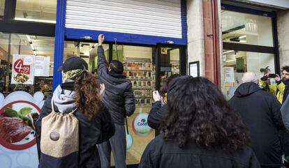 Un empleado de un supermercado baja la persiana ante la presión de los CDR en el barrio del Clot de Barcelona.