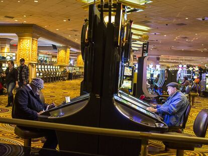 Dos personas juegan a las tragaperras en un casino en Atlantic City, Estados Unidos.