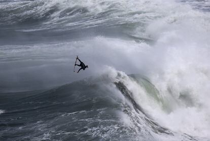 Un surfista gira en el aire durante una sesión de surf en la playa del Norte en Nazare (Portugal).