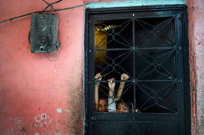 Niñas juegan detrás de la puerta en el barrio de Petare (Venezuela).