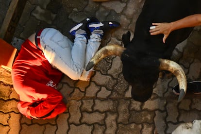 Un mozo se protege al paso de uno de los astado de la ganadería Miura, este lunes.