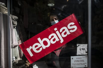 
Una empleada coloca un cartel de rebajas, en una tienda de la calle Eloy Gonzalo de Madrid. 