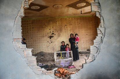 Una mujer y sus hijos están en las ruinas de su casa en la ciudad kurda de Silopi, Turquía. 