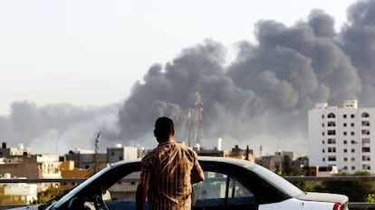 Un hombre contempla el humo que sale del aeropuerto de Tr&iacute;poli durante los combates en agosto. 
