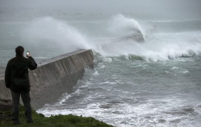 Un hombre fotografía las grandes olas que rompen en un muelle en Esquibien, en la zona oeste de Bretaña, Francia.