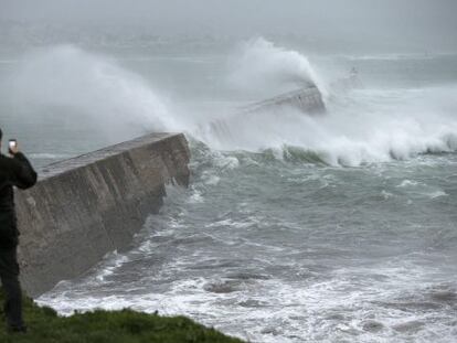 Un hombre fotograf&iacute;a las grandes olas que rompen en un muelle en Esquibien, en la zona oeste de Breta&ntilde;a, Francia.