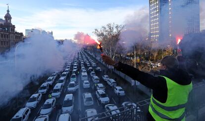 Decenas de grúas han retirado este lunes en el paseo de la Castellana taxis mientras que los agentes municipales multaban, con hasta 200 euros, a sus conductores. En la imagen, un taxista sujeta unas bengalas durante la protesta.