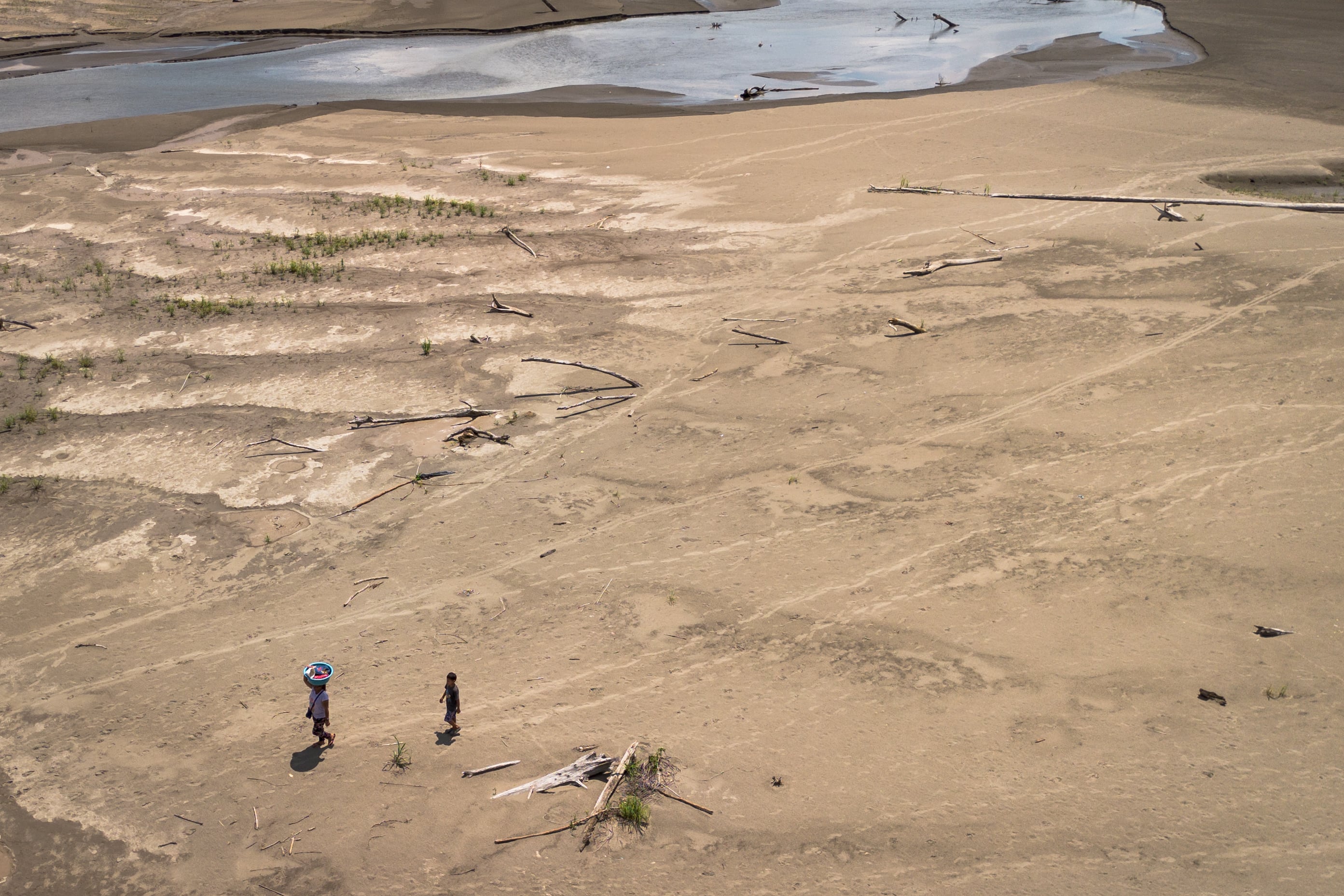 Artea Pérez y su hijo caminan por la playa seca por una sequía de regreso a su comunidad en la Amazonía peruana, en octubre pasado. 