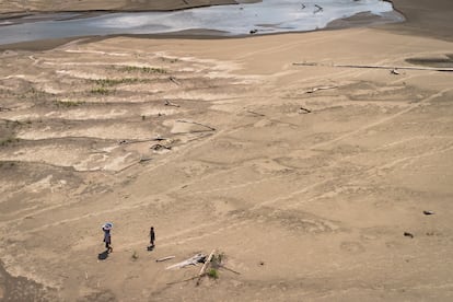 Artea Pérez y su hijo caminan bajo el sol sobre el fondo de un río que solían navegar, durante la peor sequía en la Amazonía, el 16 de octubre de 2024