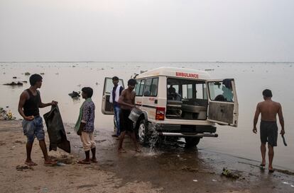 Un grupo de personas lava una ambulancia a orillas del río Ganges en Bhagalpur, estado de Bihar, el 26 de julio de 2020.