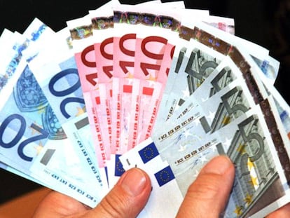 Un hombre sostiene billetes de euros en una sede del Deutsche Bank, en Alemania.