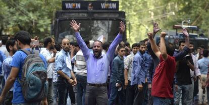 TOPSHOT - Kashmiri government teachers shout anti government slogans as Indian police spray purple coloured water during a protest in Srinagar on July 17, 2018.  Dozens of government employees were detained as they demanded hikes in salary and regularisations of their job. / AFP PHOTO / TAUSEEF MUSTAFA