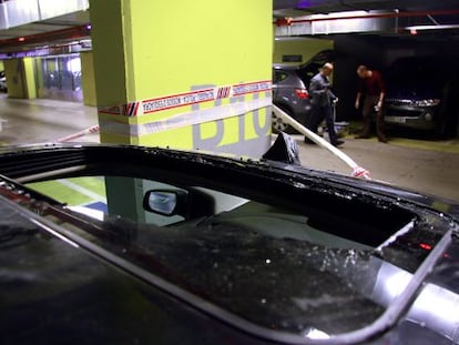 Agentes de los Mossos buscan pruebas en el aparcamiento de la estación de Sants.En primer plano, el cristal del techo roto del coche que presuntamente robó el fallecido.