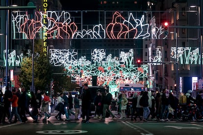 Centenares de personas caminan por la Gran Vía iluminada con las luces de Navidad, este jueves.