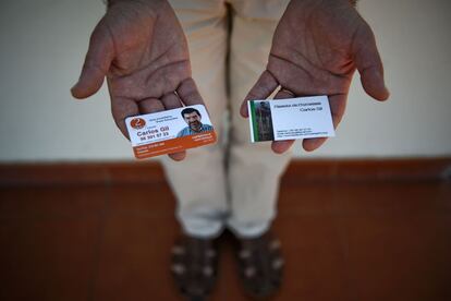 Carlos Gil muestra sus dos tarjetas de trabajo: de agente inmobiliario (izquierda) y de "pagador de promesas". Nació en Angola hace 52 años, se ganaba la vida como agente inmobiliario en Cascais hasta que decidió dejarlo.