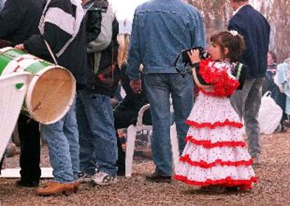 Una niña, ataviada con el traje típico andaluz, bebe agua de su cantimplora.