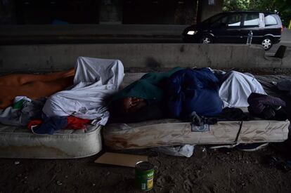 Migrantes duermen en colchones al lado de una autopista en un campo improvisado cerca de un centro para migrantes en París, Francia.