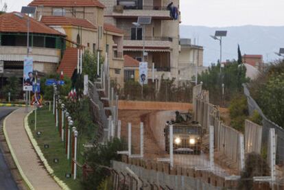 Un <i>jeep</i> israelí patrulla en la frontera con Líbano a la altura de Kfar Kila, donde se ven carteles de Ahmadineyad.