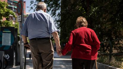 Dos ancianos caminan de la mano por una calle de Madrid.