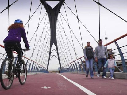 Ciclista y peatones utilizan una de las pasarelas del anillo verde ciclista de Madrid.