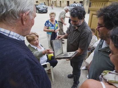 El fotógrafo examina álbumes familiares de los vecinos.