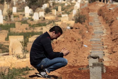 Un hombre llora junto a las tumbas de rebeldes muertos en enfrentamientos con el Ejército.